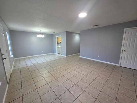 A spacious room with tile flooring and white doors.