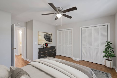 A bedroom with a bed, a ceiling fan, and a plant.
