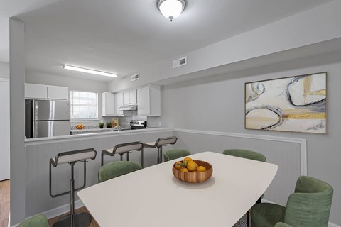 A kitchen with a table and chairs in front of a painting.