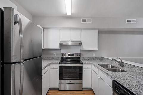 A modern kitchen with a stainless steel refrigerator and white cabinets.
