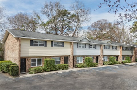 A row of townhouses with a parking lot in front.