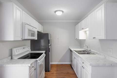 A kitchen with white cabinets and a black refrigerator.