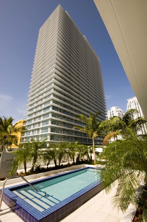 A tall building with a pool in front of it.