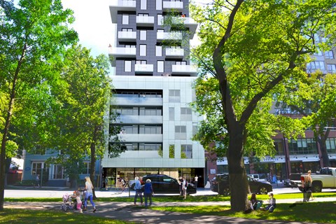 A tall white building with balconies is surrounded by trees.