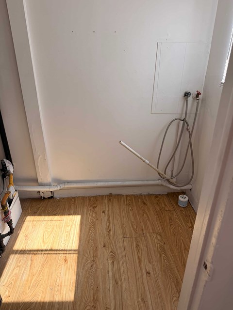 A bathroom with a wooden floor and a white wall.