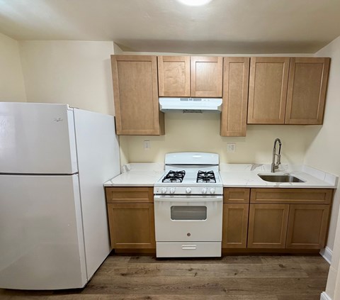 A white refrigerator sits next to a white stove in a kitchen.