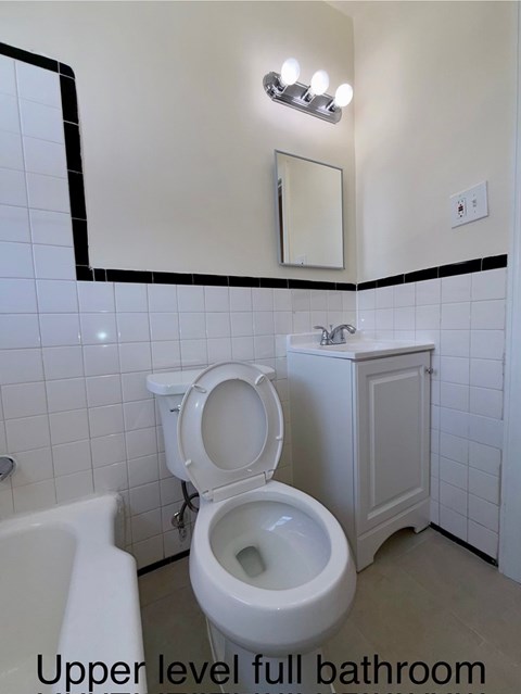 A white toilet in a bathroom with a white tub and a white sink.