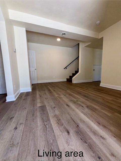 A living area with wooden flooring and a staircase.