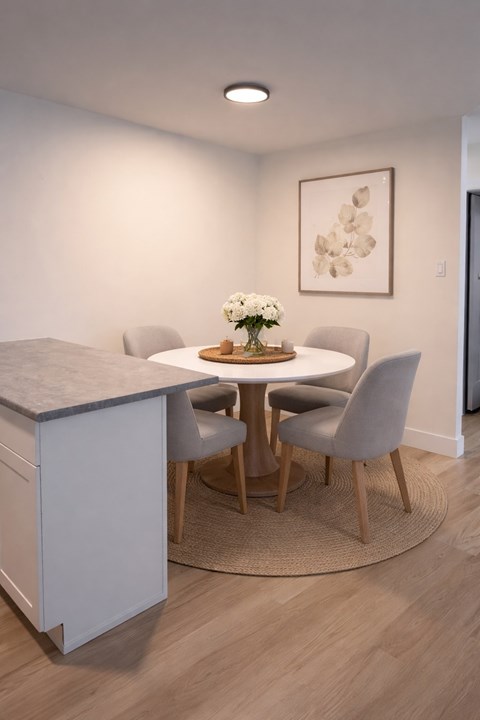 A dining room with a round table and grey chairs.