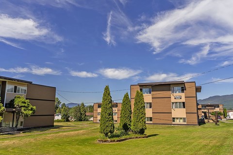 A row of apartment buildings with green lawns in front.