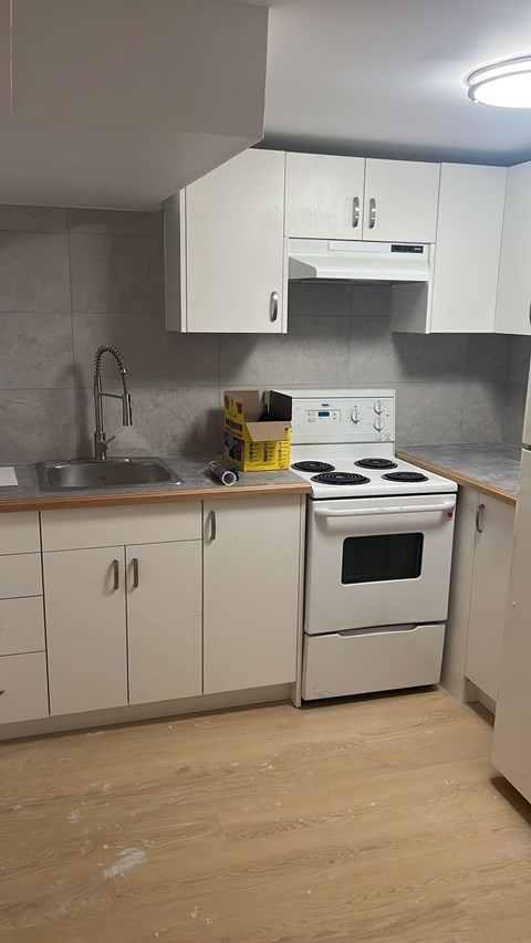 A kitchen with white cabinets and a stove top oven.