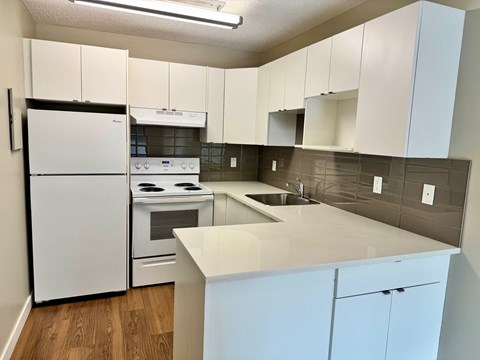 A kitchen with white cabinets and a white fridge.