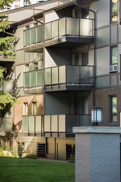 A modern apartment building with balconies and a green lawn in front.