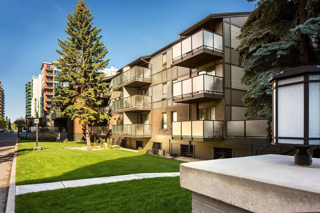 A modern apartment building with balconies and a green lawn in front.