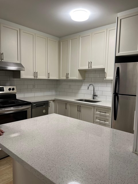 A kitchen with a white counter top and stainless steel appliances.