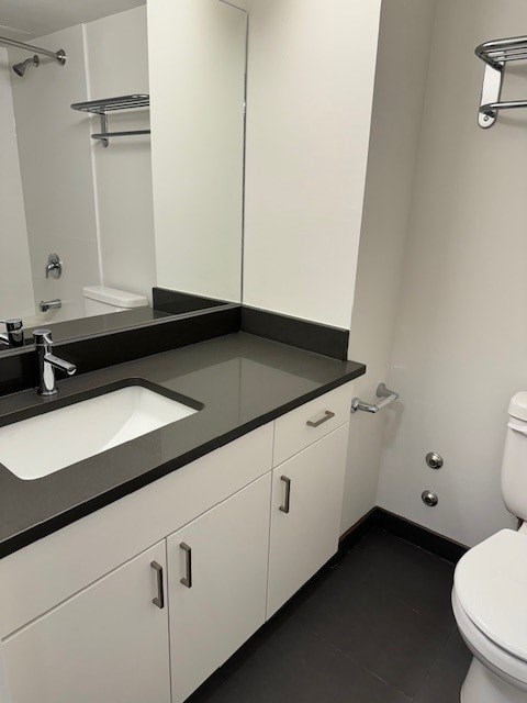 A bathroom with a sink, toilet, and a mirror.