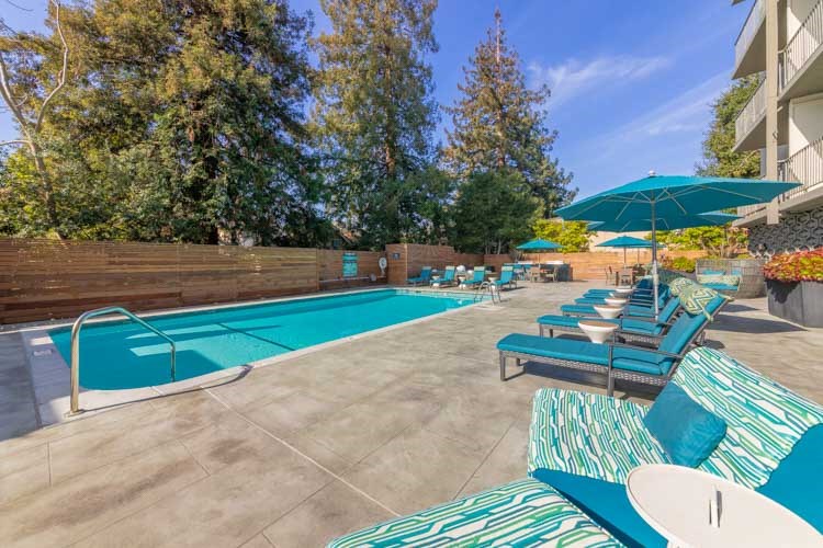 a swimming pool with blue chairs and umbrellas