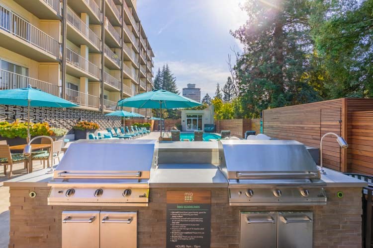 an outdoor patio with a barbecue grill and umbrellas