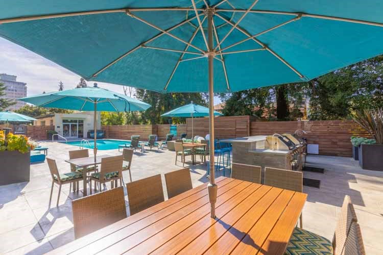 a patio with tables and umbrellas and a hot tub