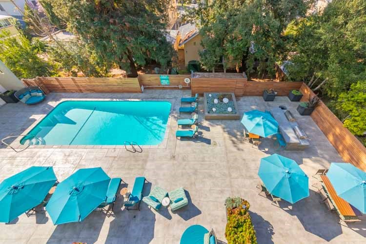an aerial view of a swimming pool with umbrellas and chairs