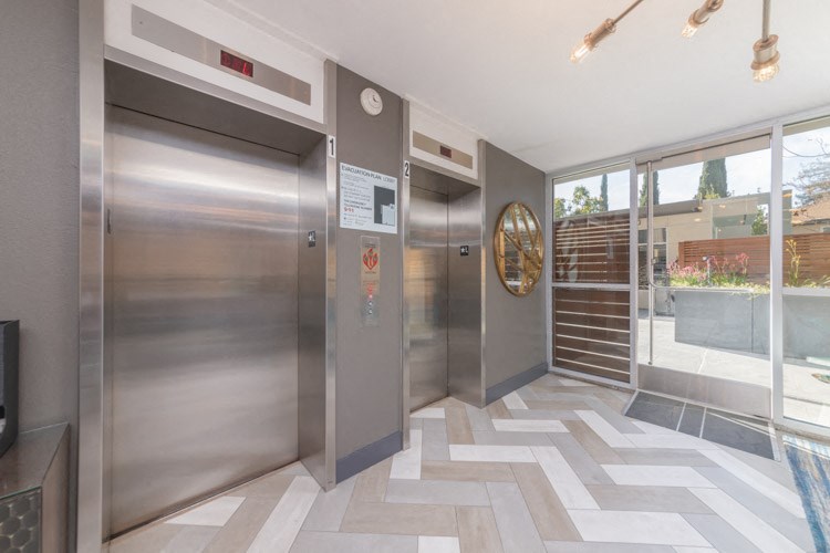 a lobby with stainless steel elevators and a checkered tile floor