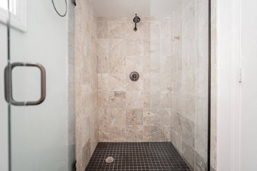 a tiled shower with a shower head in a bathroom
