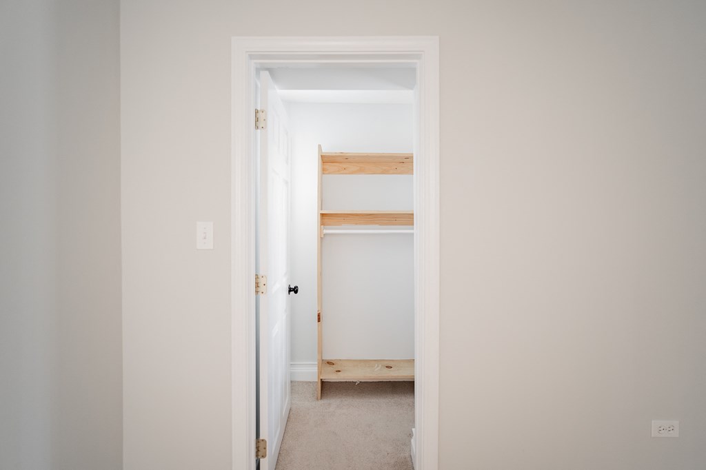 a room with a white door and a closet with shelves
