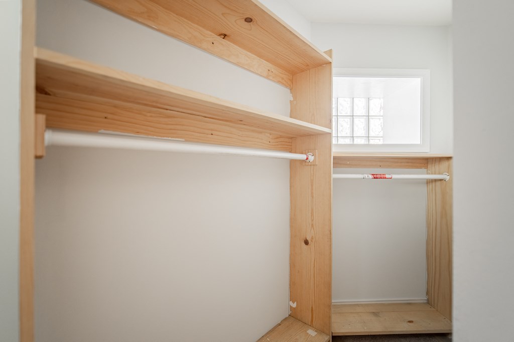 a small closet with wooden shelves and a window