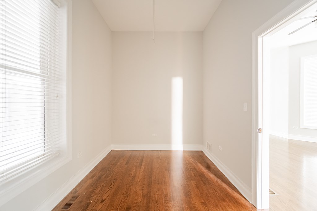 an empty living room with wood floors and white walls