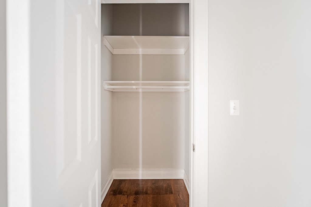an empty closet in a home with white walls and wood floors