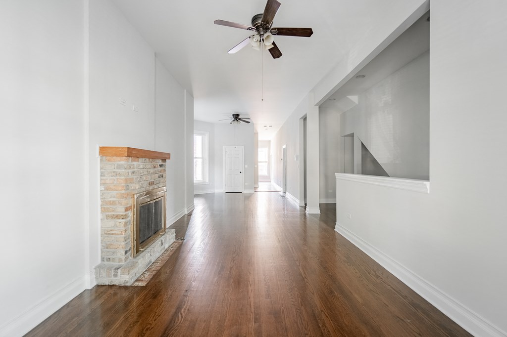 a living room with a brick fireplace and a ceiling fan
