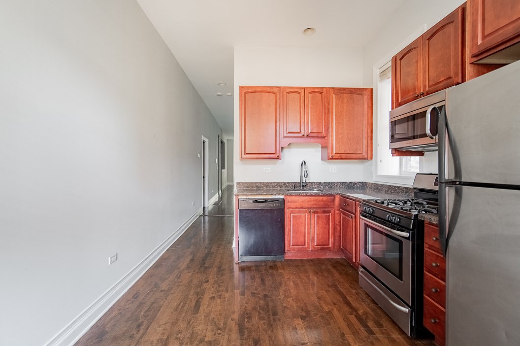an empty kitchen with wooden cabinets and stainless steel appliances