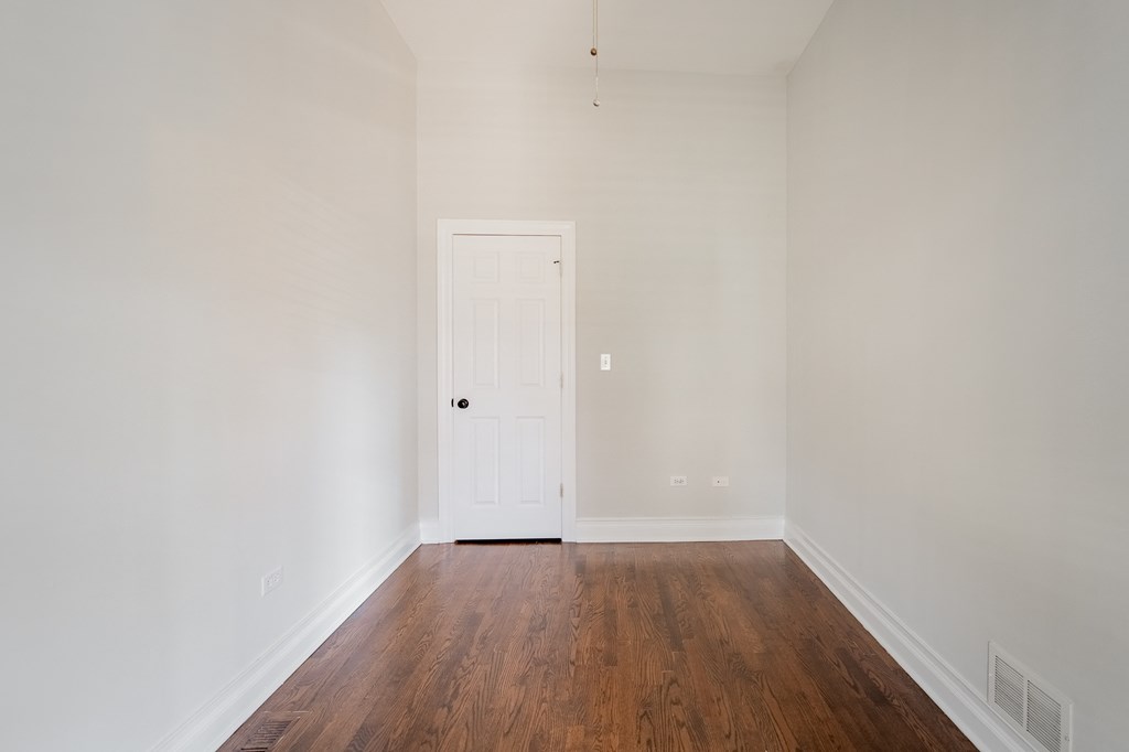 a room with white walls and a wooden floor and a white door