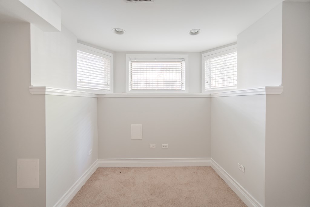an empty room with three windows and a carpet