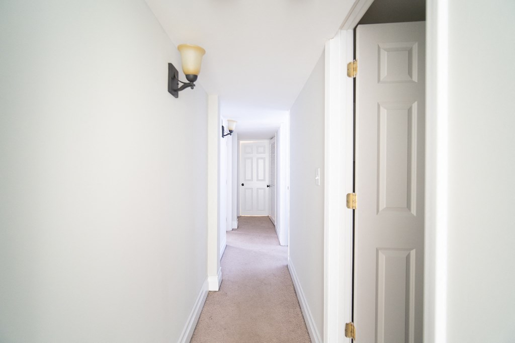 a hallway with white walls and a white door and a hallway light