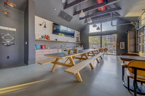 A modern kitchen with a long wooden table and benches.