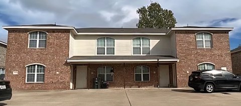A brick house with a black car parked in front.