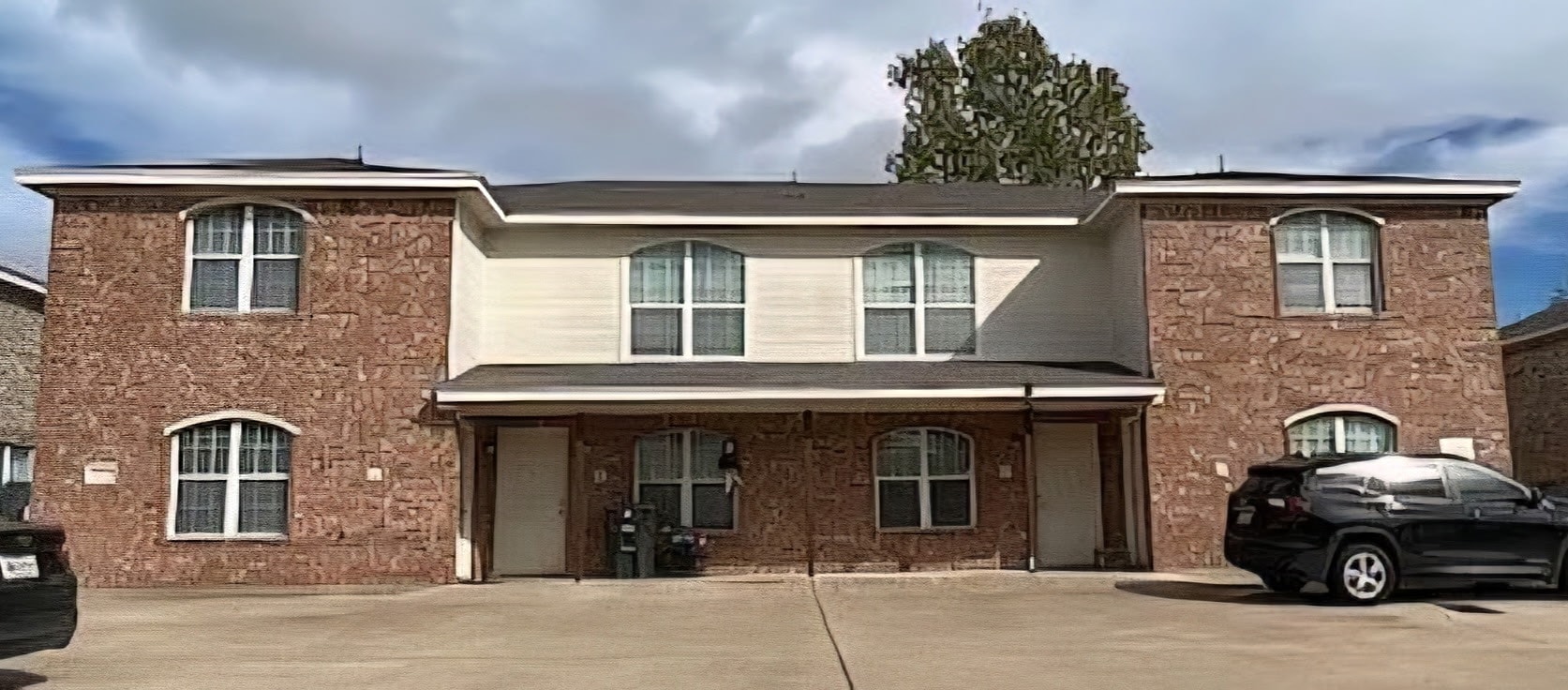 A brick house with a black car parked in front.