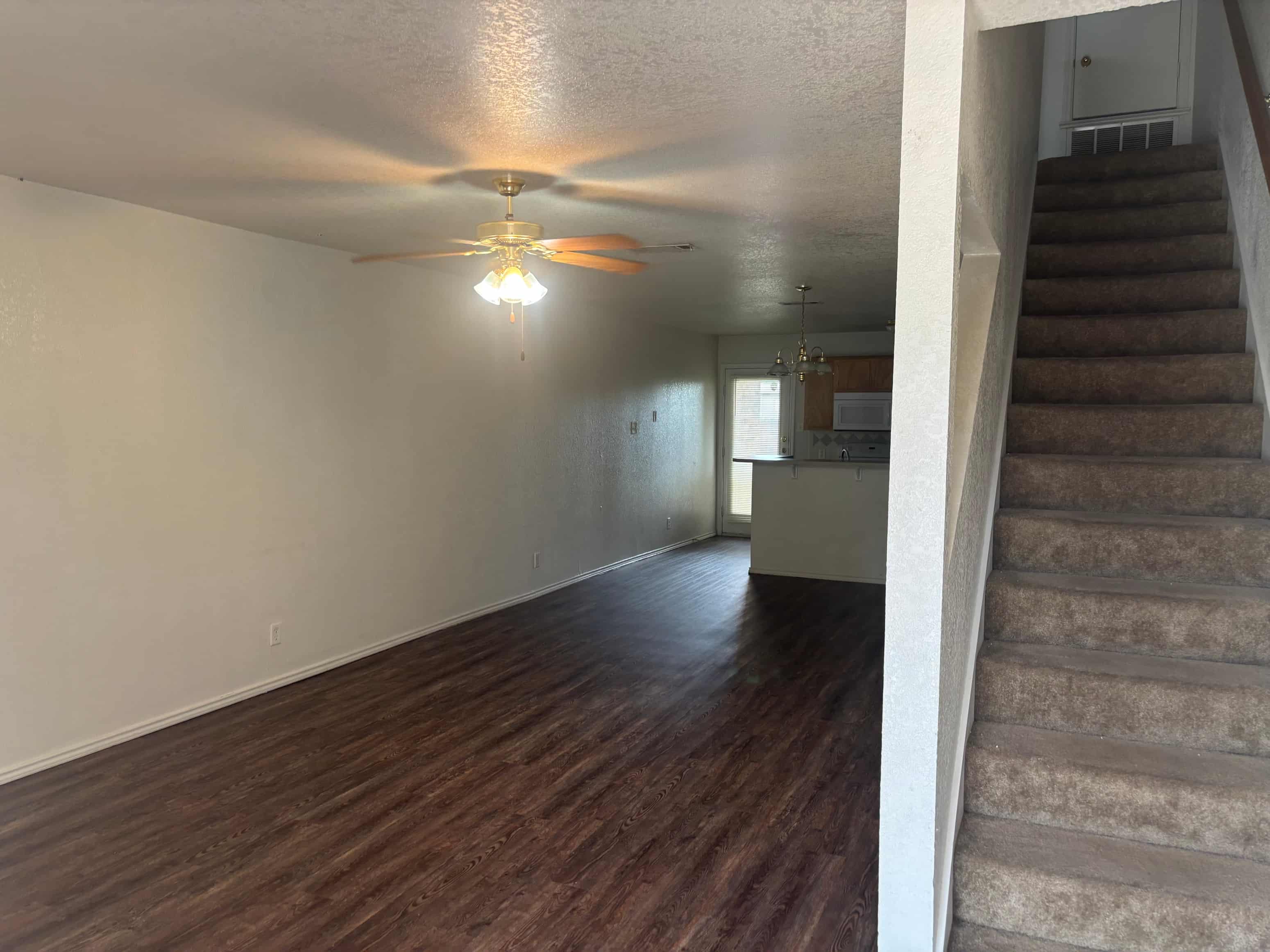 A room with a ceiling fan and wooden flooring.
