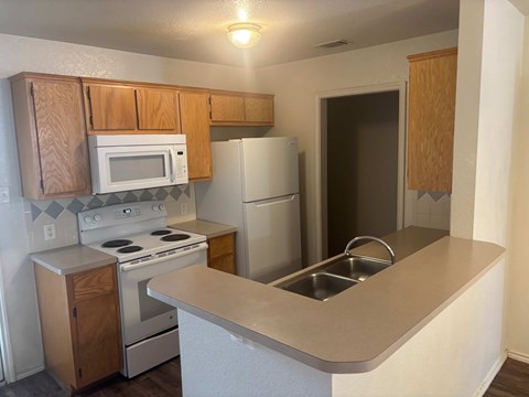A kitchen with a white refrigerator, white stove, and white microwave.