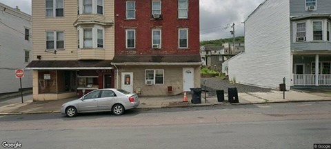 A car is parked in front of a building with a red brick facade.