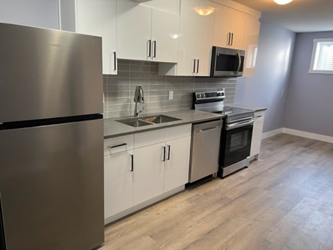 A modern kitchen with a stainless steel refrigerator and white cabinets.