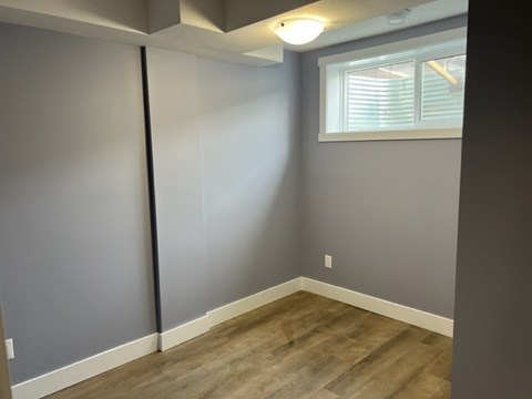 A room with wooden flooring and a window with blinds.