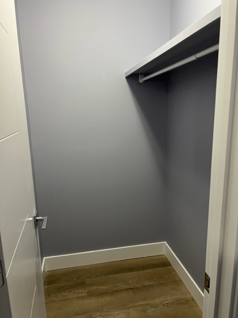 A white closet with a grey wall and wooden floor.