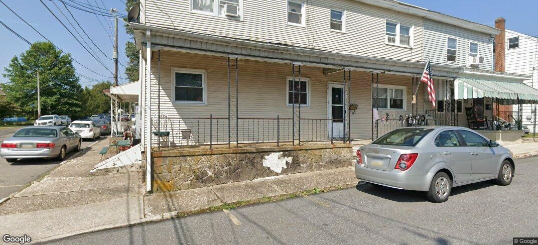A silver car is parked in front of a house.