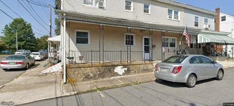 A silver car is parked in front of a house.
