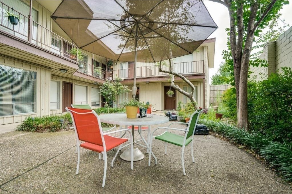 A patio with a table and chairs under an umbrella.