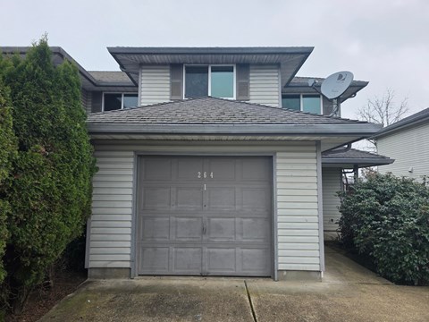 A house with a grey garage door and a satellite dish on the roof.