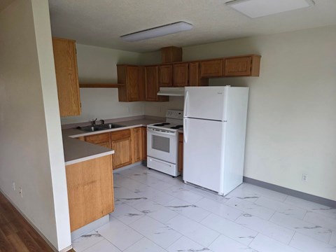A kitchen with white appliances and wooden cabinets.
