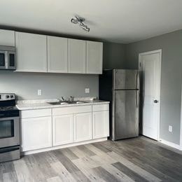 A kitchen with white cabinets and a stainless steel refrigerator.